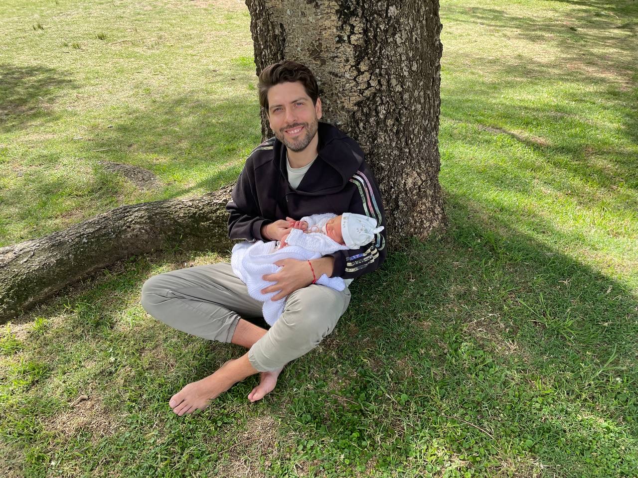 Danilo Rodríguez sosteniendo a su bebé bajo un árbol