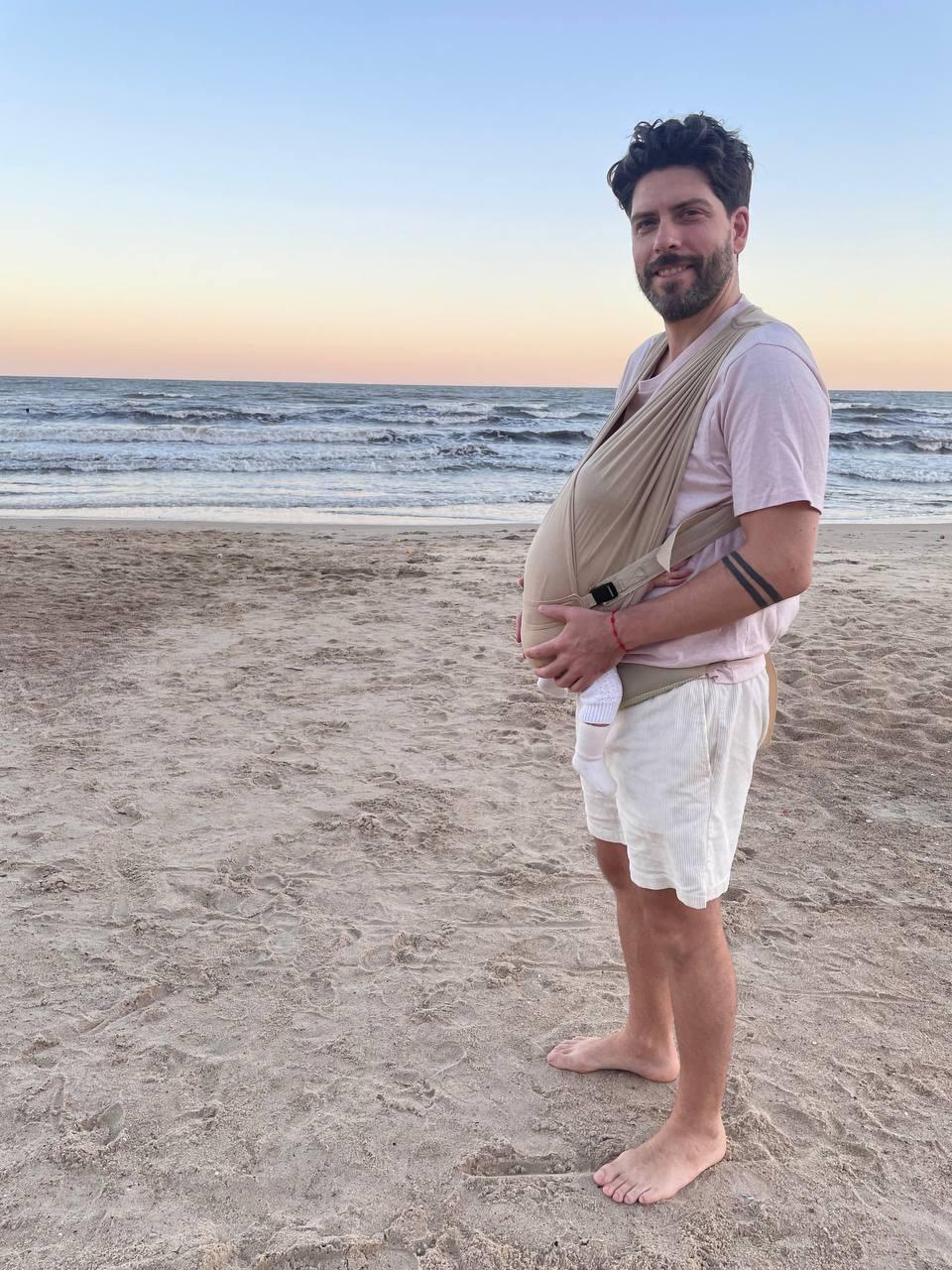 Danilo Rodríguez en la playa con su bebé en porteo